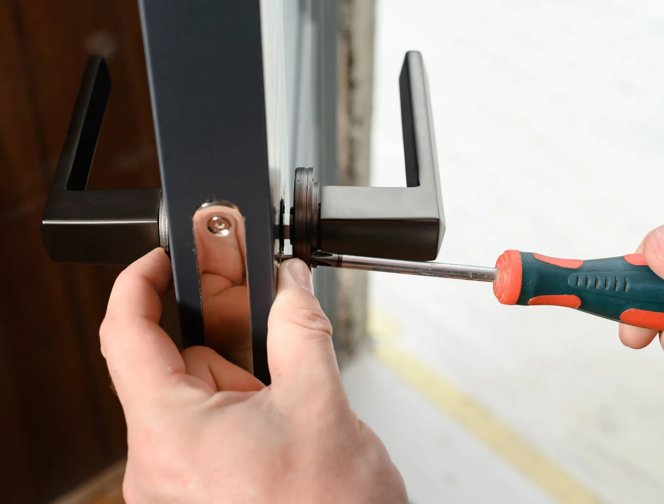 man fixing a door handle by using a screw driver.