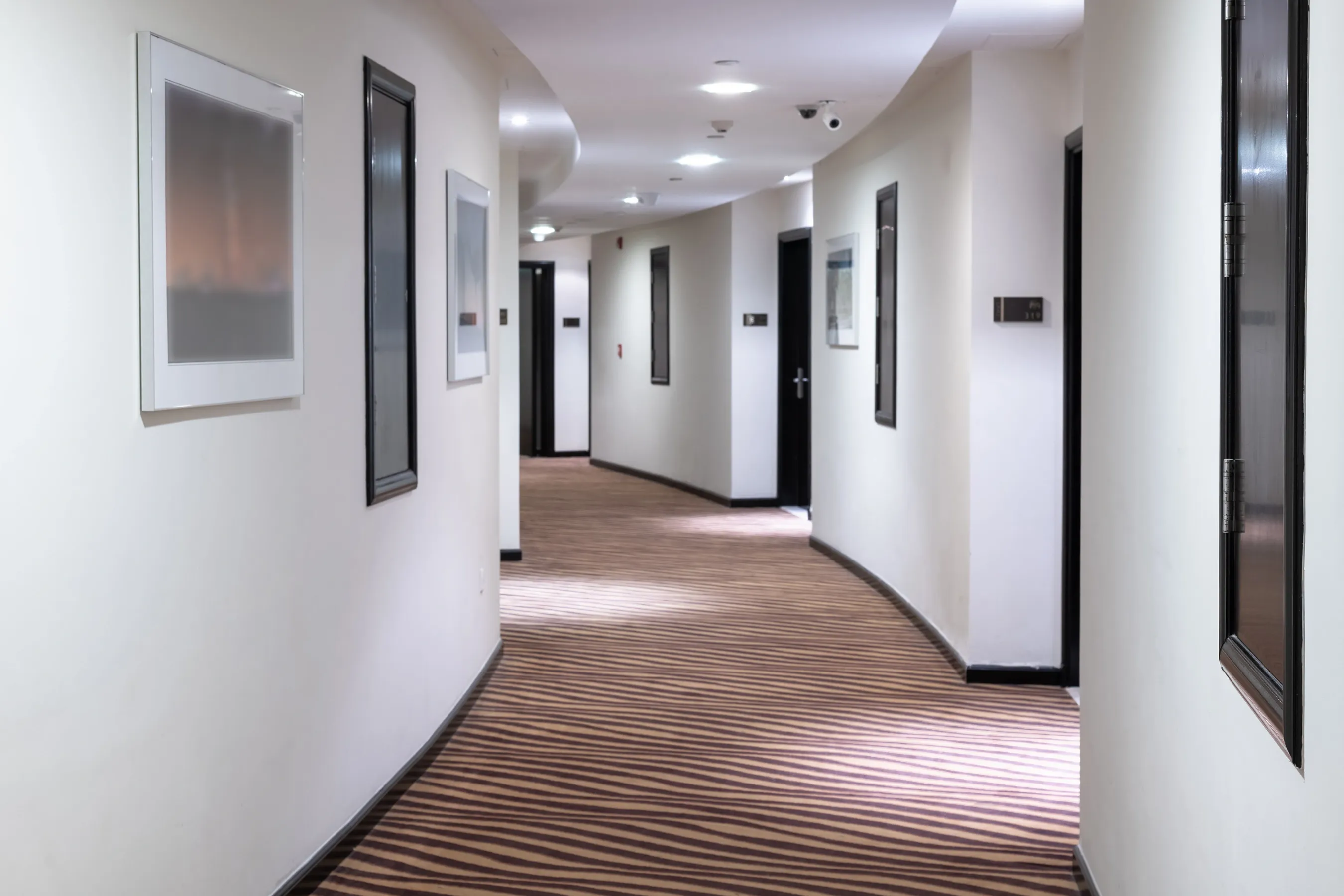 hotel hallway with white walls and black trim.