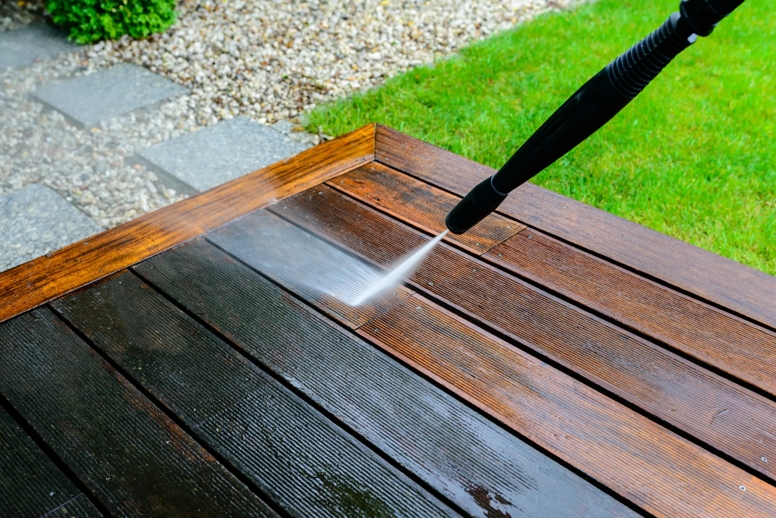 power washing a wood deck to get rid of grime and dirt.